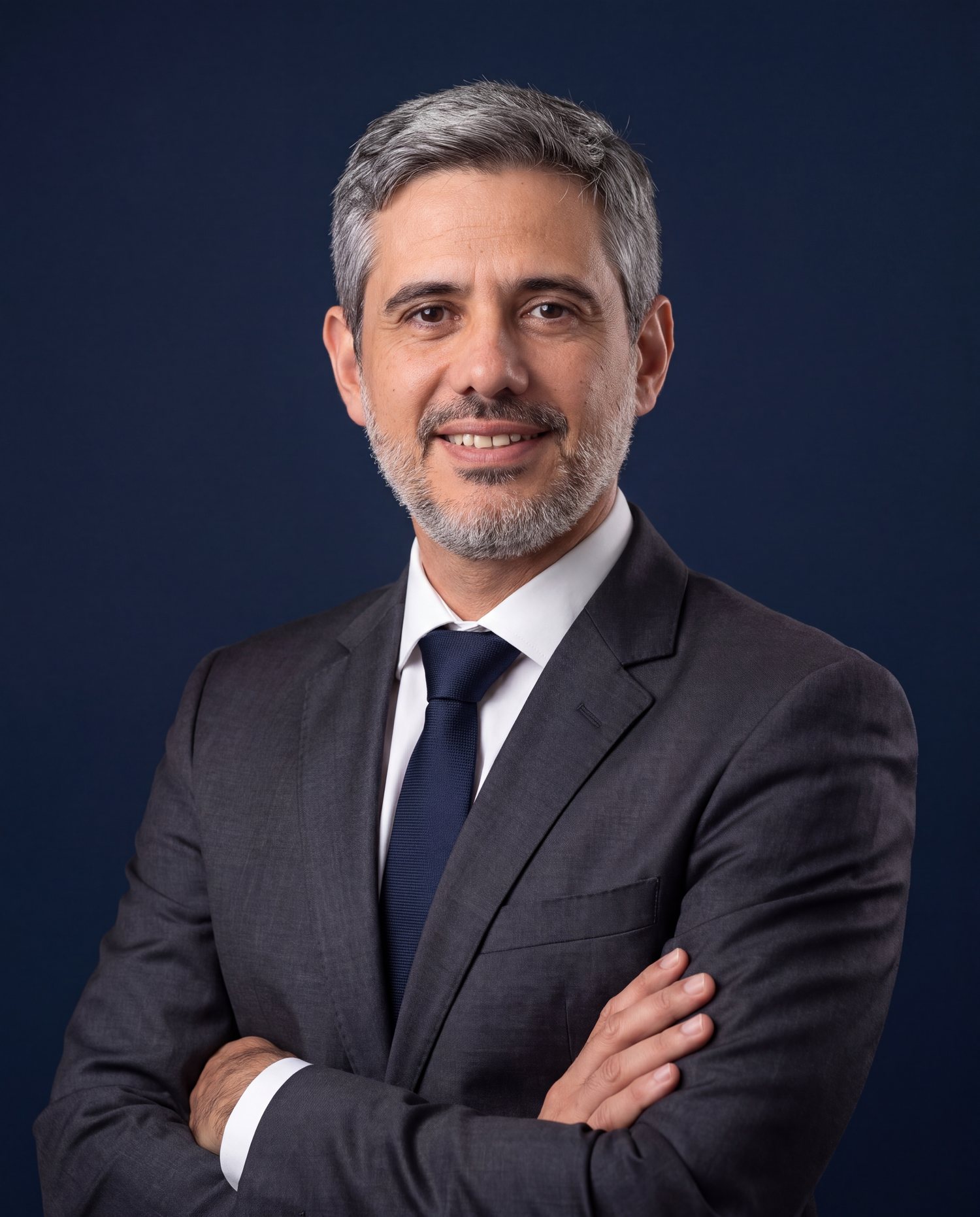 Dr. Cláudio Almeida Parra de terno, em fundo azul-marinho